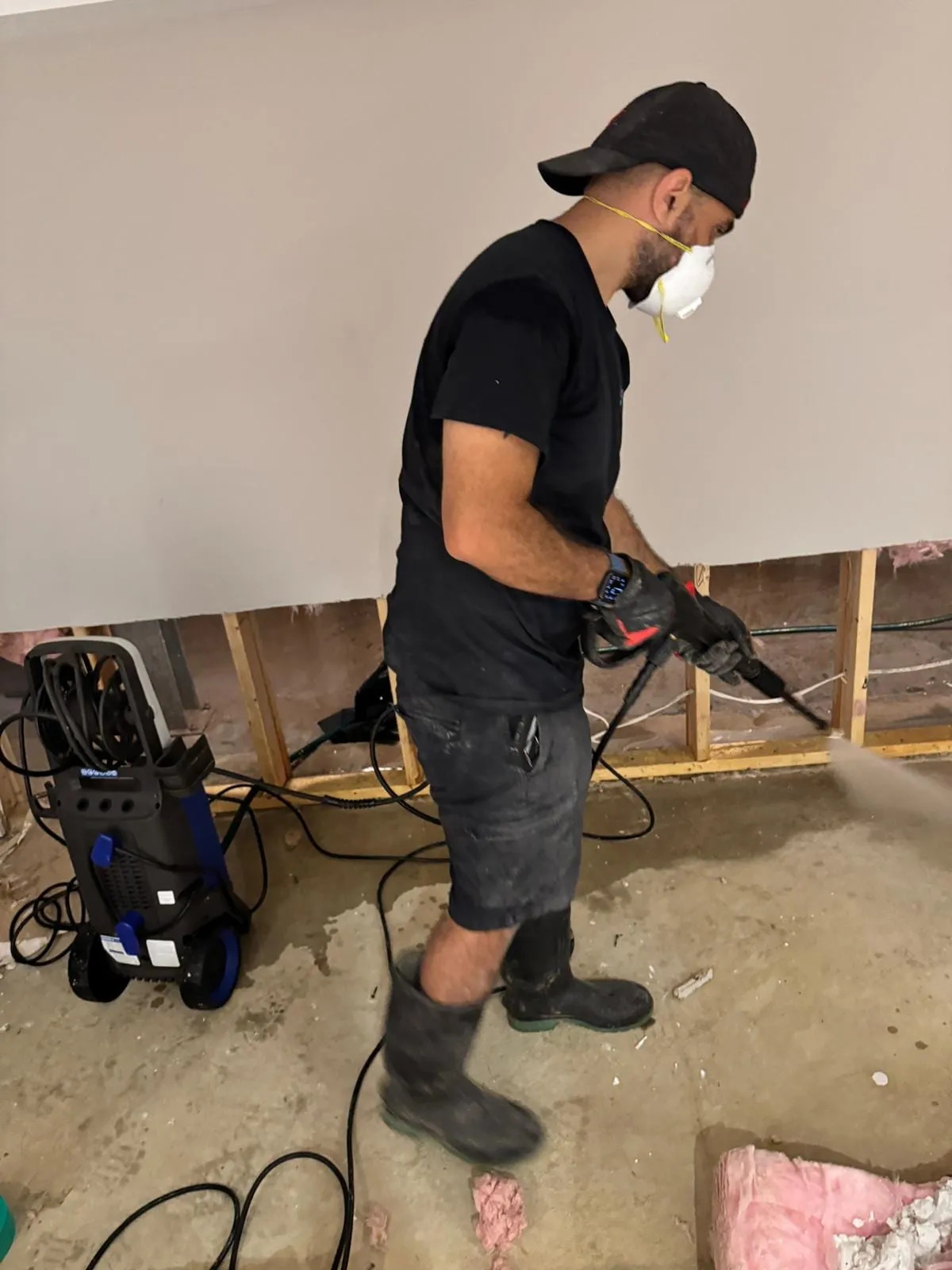 Technician cleaning exposed studs after a flood cut