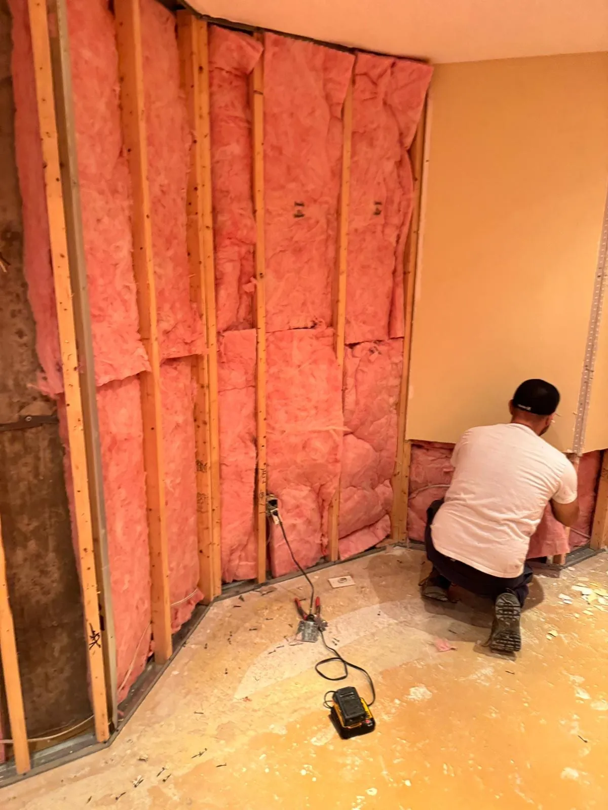Technician removing wet insulation from an opened basement wall